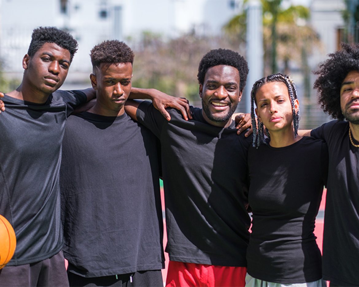 Young friends with urban style playing basketball on multicolore