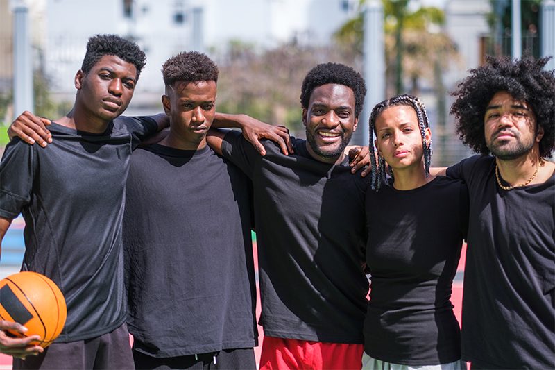 Young friends with urban style playing basketball on multicolore